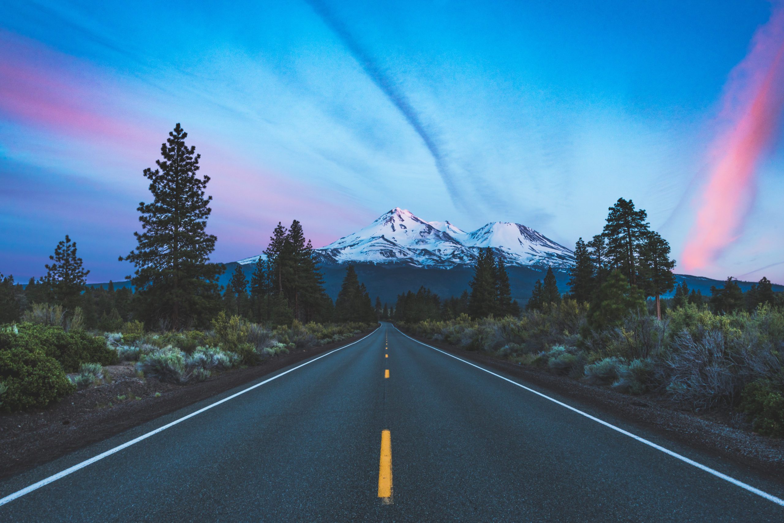 A road leading to snow-capped mountains at sunrise